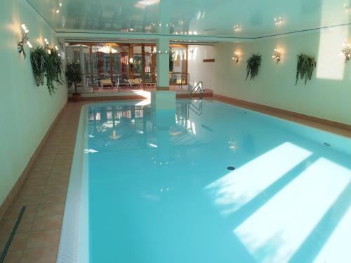 - une piscine intérieure avec éclairage bleu dans un bâtiment dans l'établissement Parkhotel zum Stern, à Oberaula