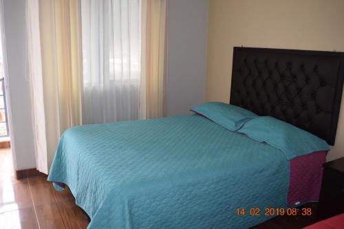 a bedroom with a bed with a blue comforter at Arum Qurpawasi Hospedaje in Cabanaconde