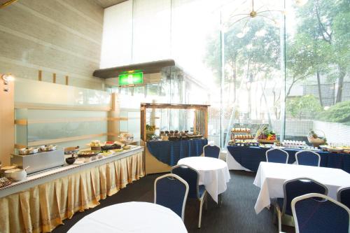 大垣市にあるクインテッサホテル大垣のテーブルと椅子のあるレストラン、食べ物を取り揃えたカウンター