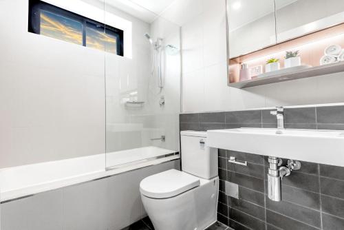 Baño blanco con aseo y lavamanos en G3 Apartment en Brisbane
