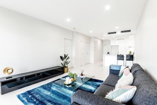 uma sala de estar com um sofá e uma mesa de vidro em G3 Apartment em Brisbane