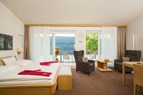 a hotel room with a bed and a desk and chairs at BRUGGER'S Hotelpark am See in Titisee-Neustadt