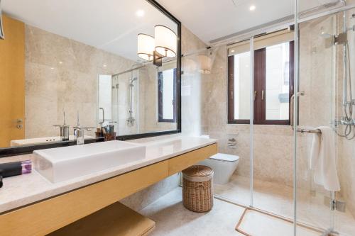 a bathroom with a sink and a shower and a toilet at HaitangBay Loosen Coast Resort Villas in Sanya
