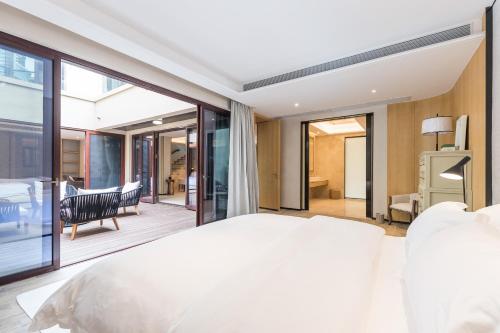 a bedroom with a large white bed and a balcony at HaitangBay Loosen Coast Resort Villas in Sanya