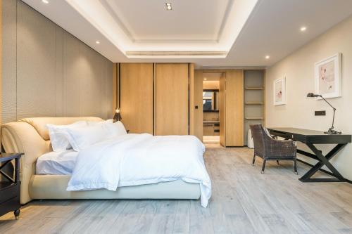 a bedroom with a white bed and a desk at HaitangBay Loosen Coast Resort Villas in Sanya