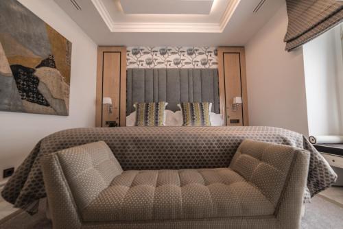 a bedroom with a large bed and a couch at Hotel Casa Palacio María Luisa in Jerez de la Frontera