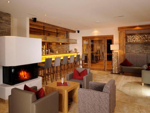 a living room with a fireplace and a bar at Hotel Garni Alpenjuwel in Serfaus