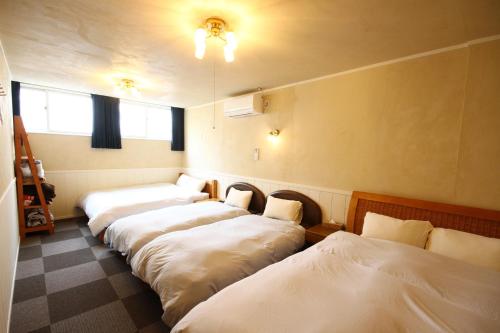 a row of four beds in a room at kODATEL コダテル 札幌大通公園 アネックス in Sapporo
