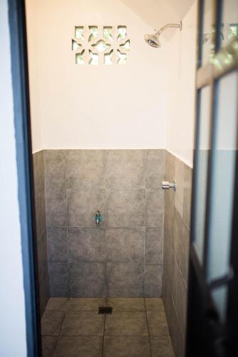 a bathroom with a shower with a tiled floor at Avisala Hostel Coron in Coron