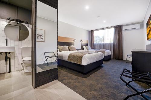 a hotel room with a bed and a mirror at CBD Motor Inn in Coffs Harbour