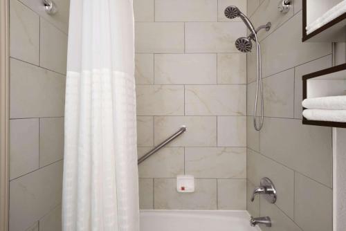 baño con ducha con cortina blanca en Howard Johnson by Wyndham Appleton en Appleton