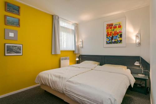 - une chambre avec un lit et un mur jaune dans l'établissement Quo Vadis, à Grou