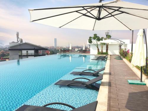 a swimming pool with lounge chairs and an umbrella at Mandala Hotel & Spa Bac Ninh in Bắc Ninh