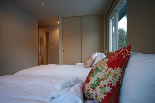 een slaapkamer met een bed met rode en witte kussens bij ASANOHA in Furano