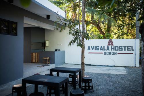 un grupo de mesas y taburetes frente a un edificio en Avisala Hostel Coron en Corón