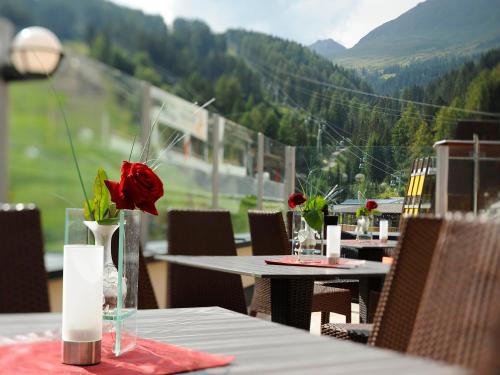 a table with roses in a vase on a table with a view at Hotel Garni Alpenjuwel in Serfaus
