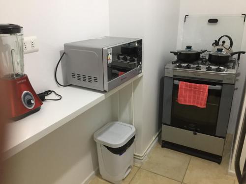 un four micro-ondes assis sur un comptoir à côté d'une cuisinière dans l'établissement Departamento Quilpué, à Quilpué