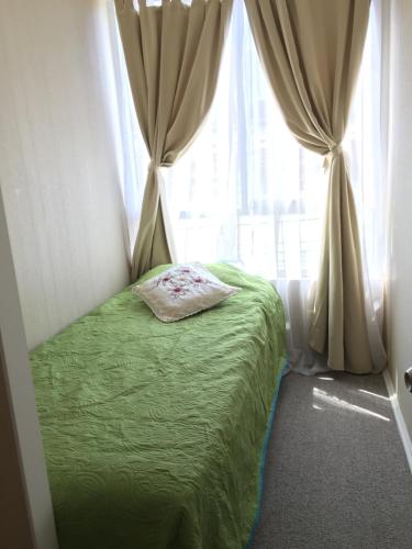 - une chambre avec un lit vert et une fenêtre dans l'établissement Departamento Quilpué, à Quilpué