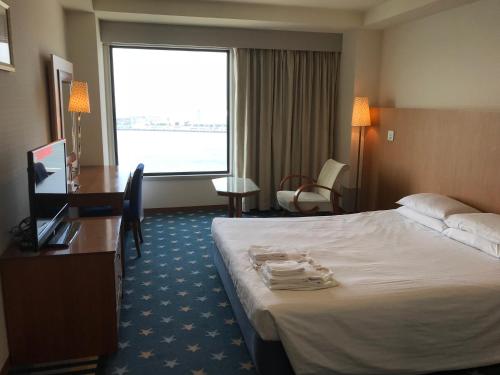 a hotel room with a bed and a desk and a window at Hotel Seagull Tenpozan Osaka in Osaka