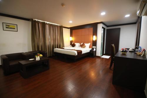ein Hotelzimmer mit einem Bett und einem Sofa in der Unterkunft BROAD BEAN KANNUR in Kannur
