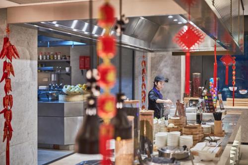 a chef preparing food in a restaurant kitchen at Hyatt House Chengdu Pebble Walk in Chengdu