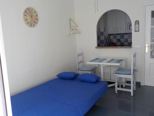 1 dormitorio con cama azul y escritorio en By The Sea, en Nerja