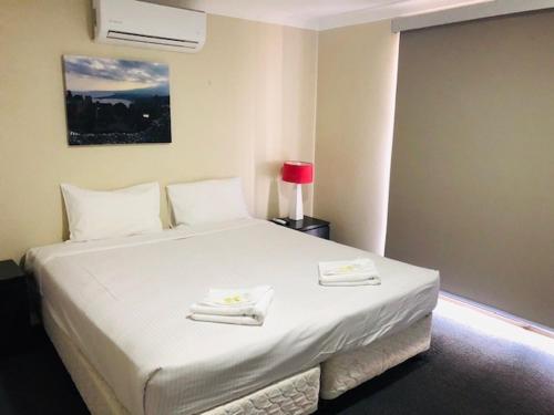 a bedroom with a white bed with two towels on it at Huskisson Beach Escape in Huskisson