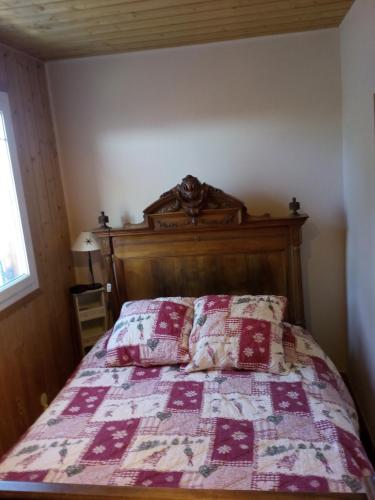 una cama con cabecero de madera y dos almohadas en Greselin, en Chorges