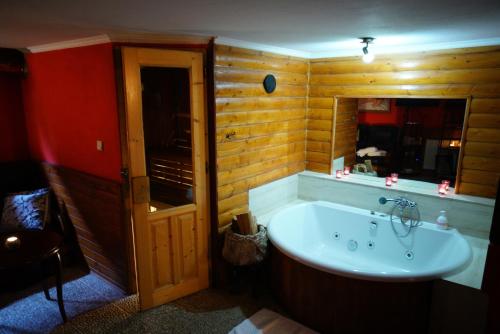 a bathroom with a tub in a room with wooden walls at Penzion Restaurant Jakub in Poprad