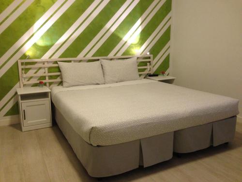 a white bed in a room with a green wall at B&B Homer Trento in Trento