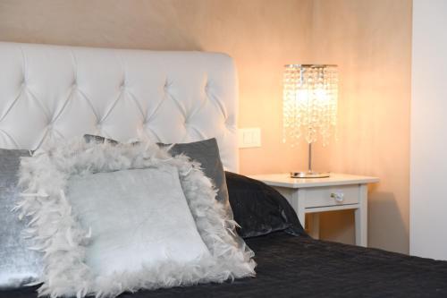 a bed with a white headboard with a white pillow at Luxury Suite Sirmione in Sirmione