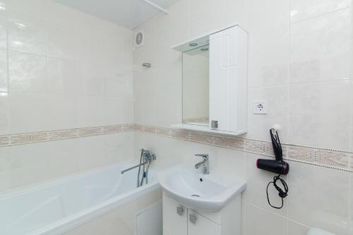 een witte badkamer met een wastafel en een spiegel bij 16 вулиця Прокоф'єва in Sumy