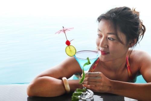 a woman sitting in the water with a drink at Balcona Hotel Da Nang in Da Nang