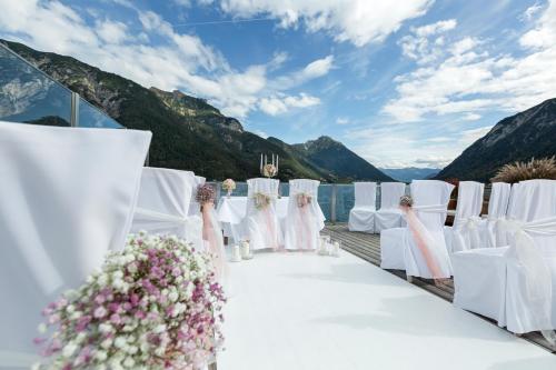 a wedding aisle with white chairs and flowers at Entners am See in Pertisau