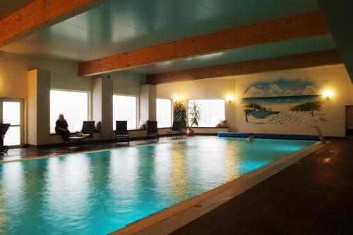 a swimming pool in a hotel with a person sitting in a chair at Ferienresort Texas MV in Kirch Jesar