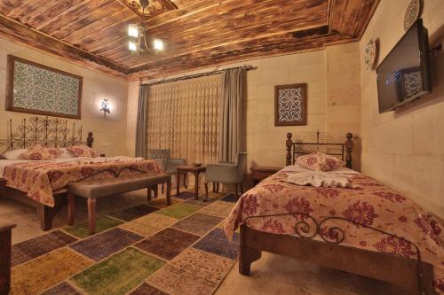 a bedroom with two beds and a tv on the wall at Caravanserai Inn Hotel in Goreme