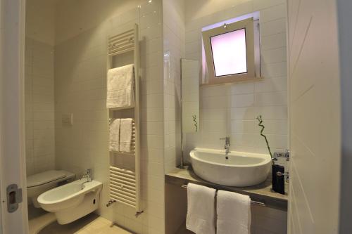 a white bathroom with a sink and a toilet at Foresteria Pellegrino in Andria