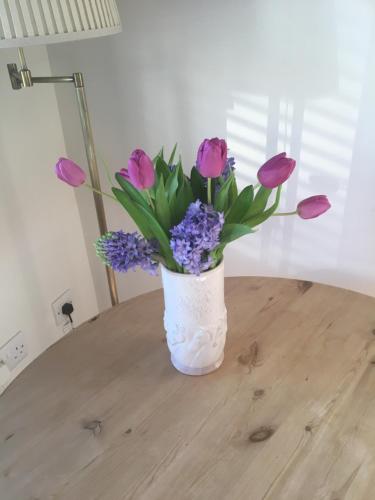 a vase filled with purple and purple flowers on a table at Little Banks Barn in Ringwood