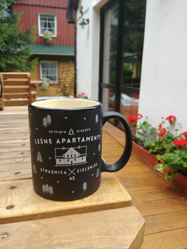 a black coffee cup sitting on a wooden table at Leśne Apartamenty in Zieleniec