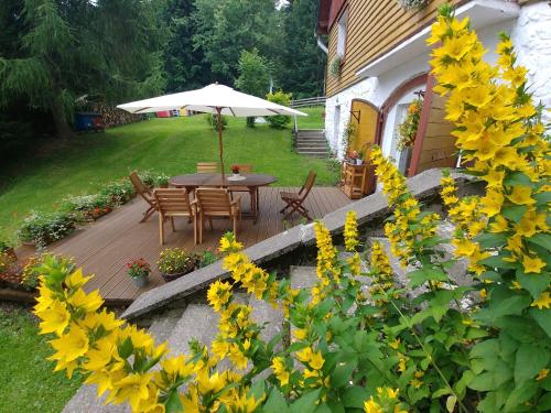a wooden deck with a table and chairs and an umbrella at Leśne Apartamenty in Zieleniec