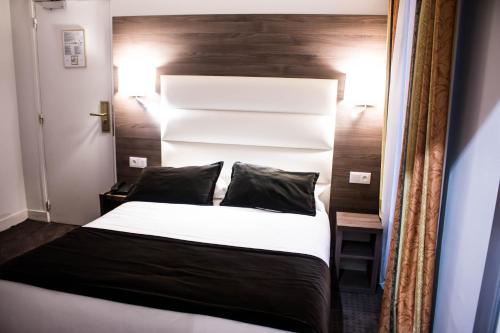 a bedroom with a white bed with a wooden headboard at Hotel Agenor in Paris