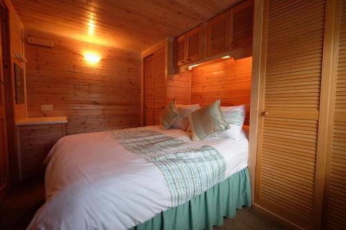 a bedroom with a white bed with wooden walls at Fellside Lodge in Keswick
