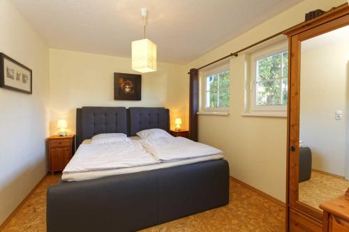 a bedroom with a bed with a blue headboard and two windows at Zinnowitz Skanepark Ferienhaus 28 in Zinnowitz