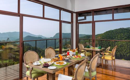 een eetkamer met een tafel, stoelen en ramen bij Anasa Wellness Resort in Ella