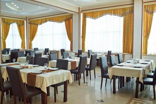un comedor con mesas, sillas y ventanas en Grand Nakhchivan Hotel, en Najicheván