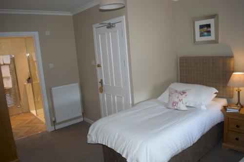 a bedroom with a bed with white sheets and pillows at Balnearn House in Aberfeldy