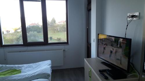a room with a flat screen tv and windows at Guest House Panorama in Gela