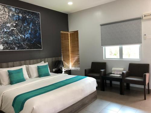 a bedroom with a large bed and two chairs at Fuuka Villa in Pantai Cenang