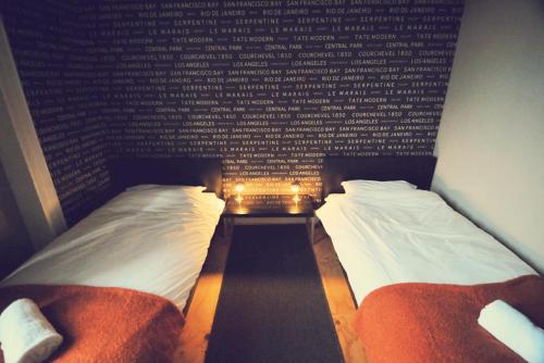 two beds in a room with a wall with words at Vagabonds Hostel in Belfast