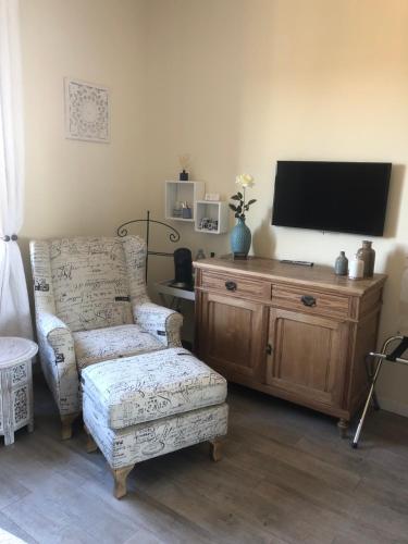 a living room with a chair and a flat screen tv at Les Secrets du Mistral in Valensole